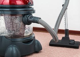 Close-up of a modern vacuum cleaner with water filtration on carpet floor indoors.